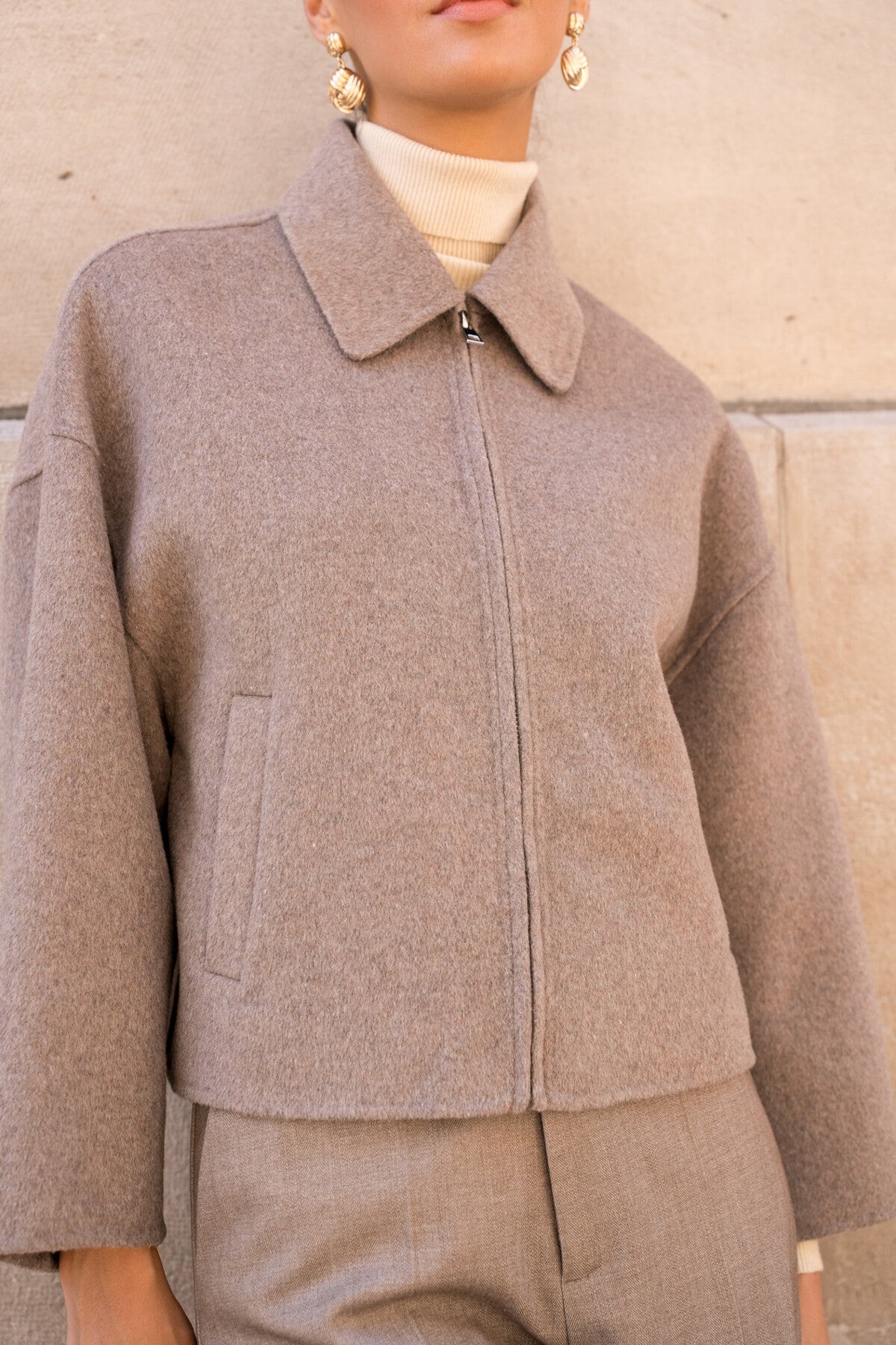 Close-up of shirt collar and zip detail on taupe wool-blend women’s coat.