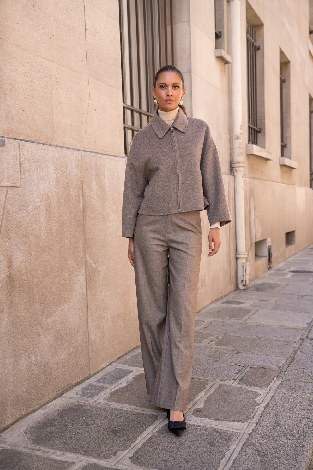 short taupe coat showing flared long sleeves and soft fabric.