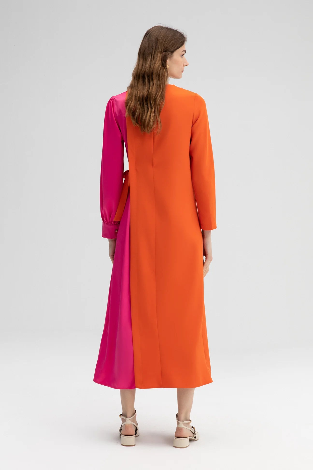 Back of the model wearing pink and orange colour block midi dress with long sleeves