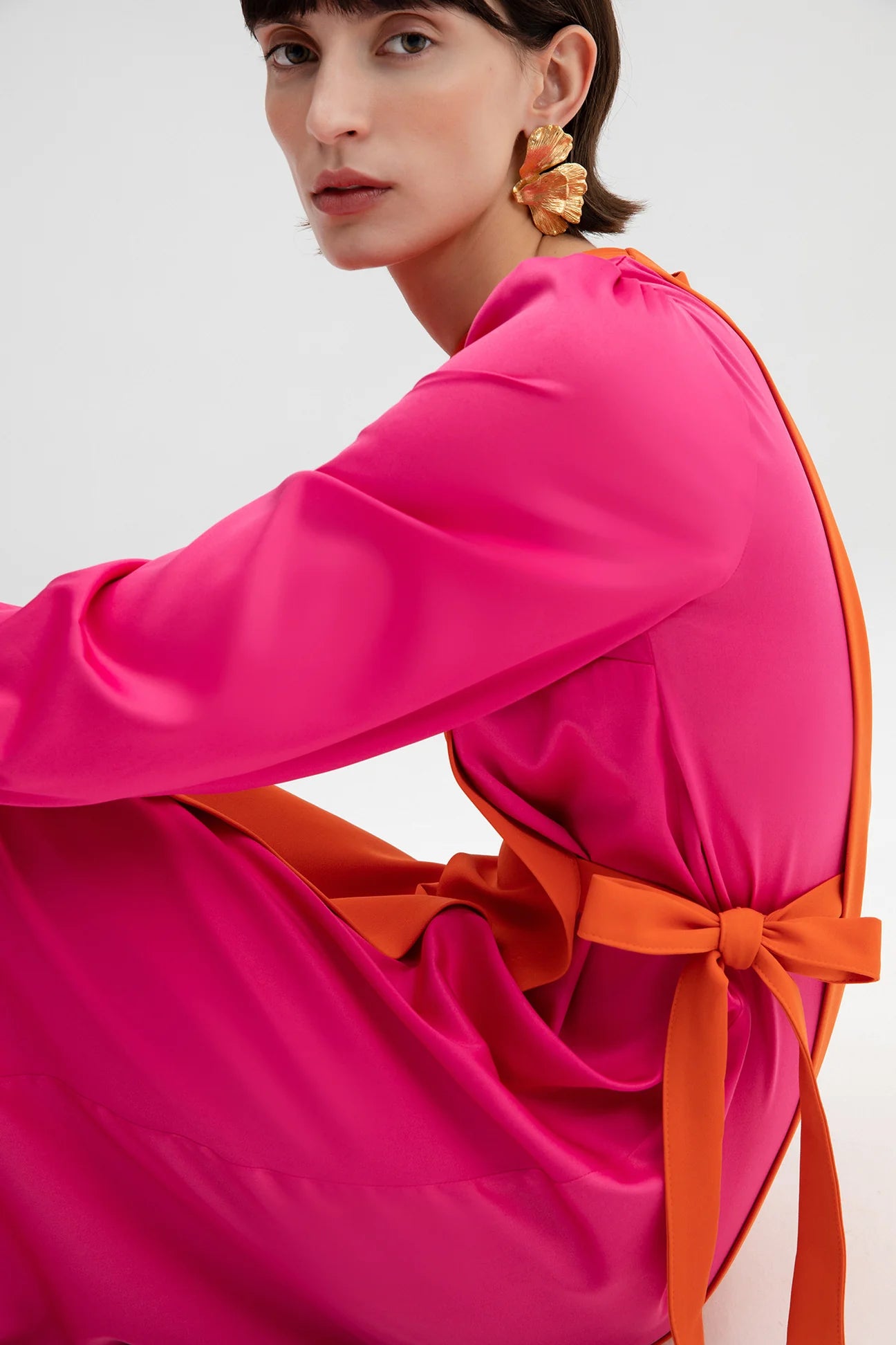 Side view of fuchsia and orange statement dress with satin finish