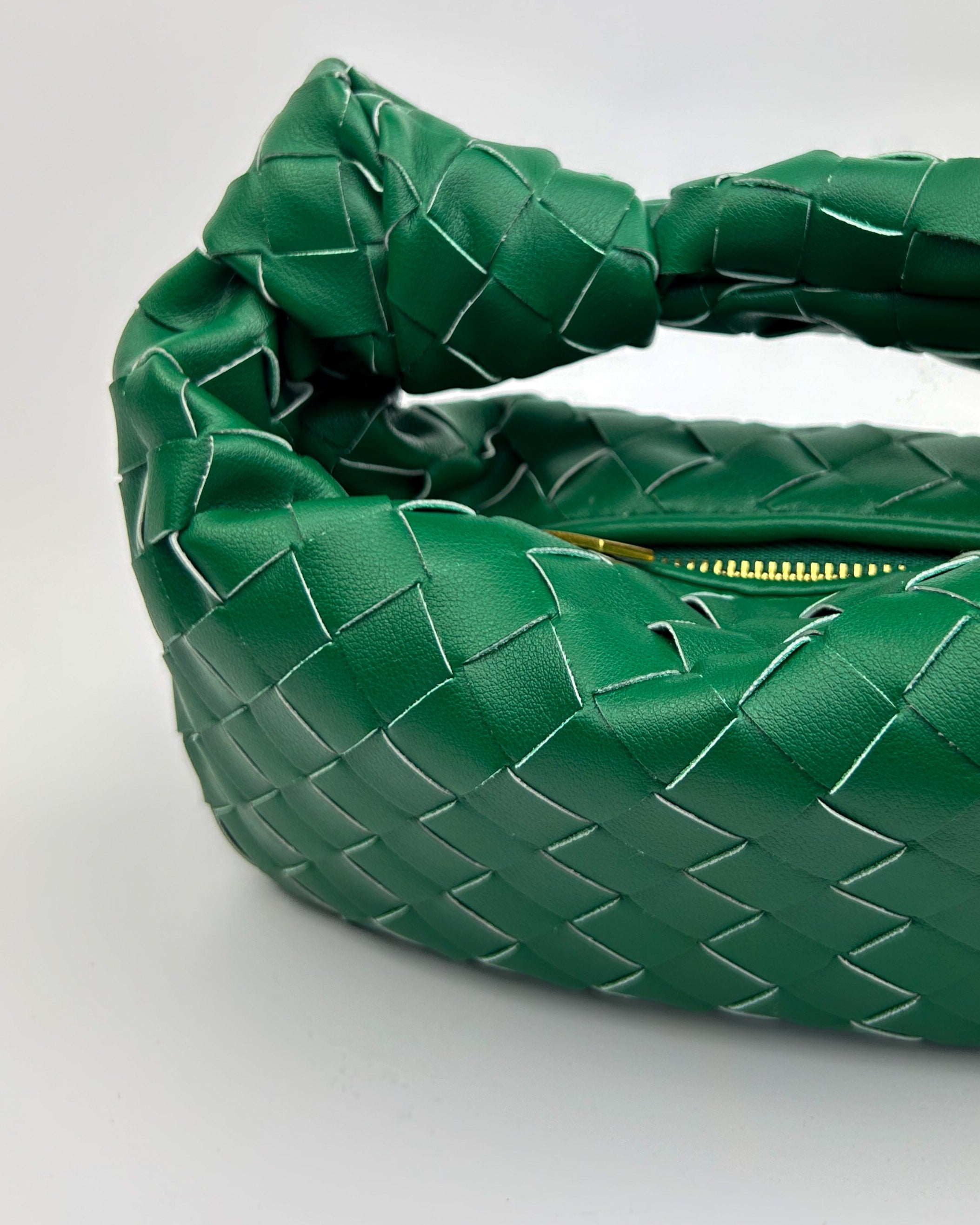 Side view of green crescent-shaped leather handbag, handcrafted in Italy with sculptural structure