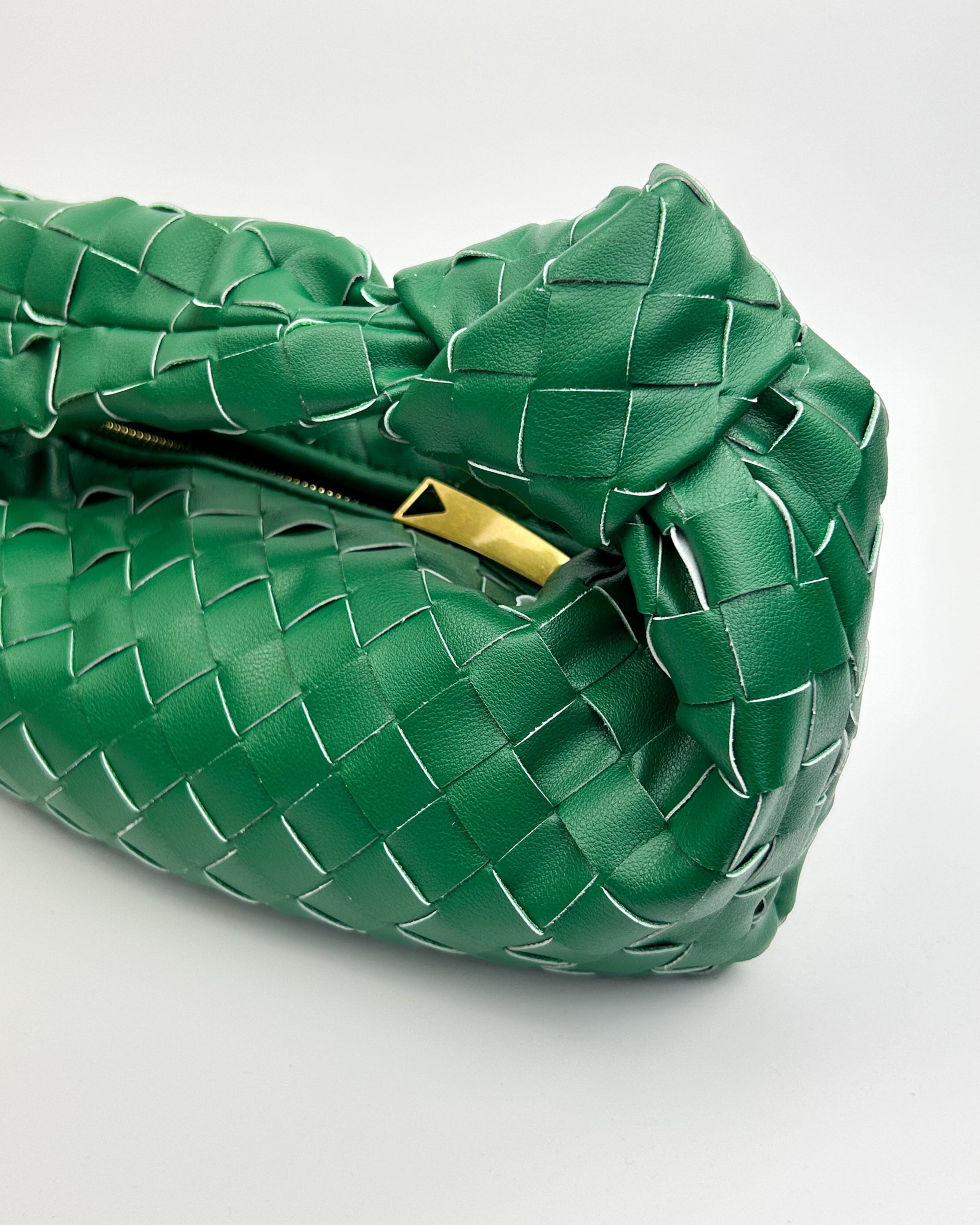 Interior of The Knot Woven Bag in green showing zip closure, full lining, and inner slip pocket in luxury leather finish