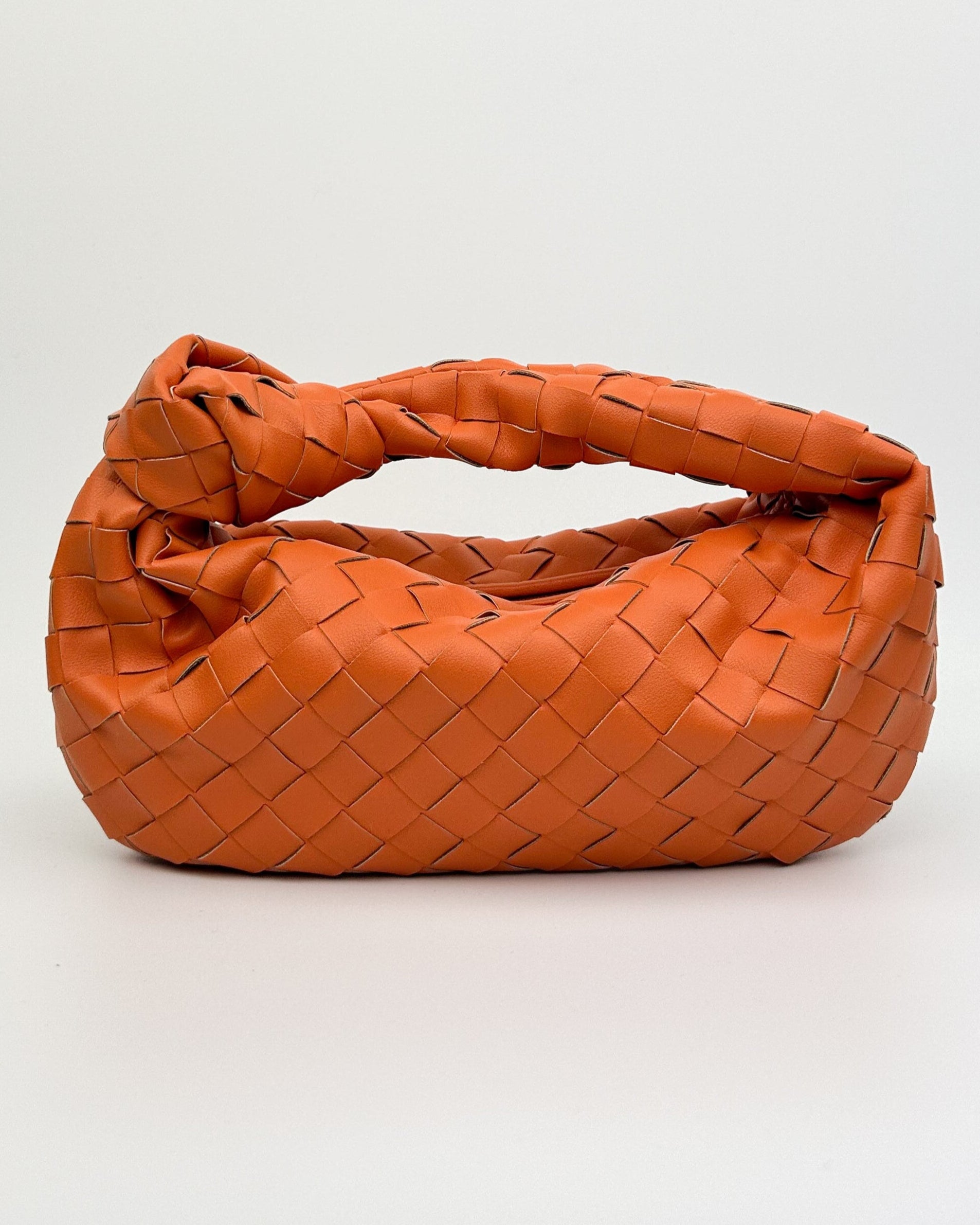 Front view of The Knot Woven Bag in orange, Italian calf leather with bold woven texture and crescent silhouette