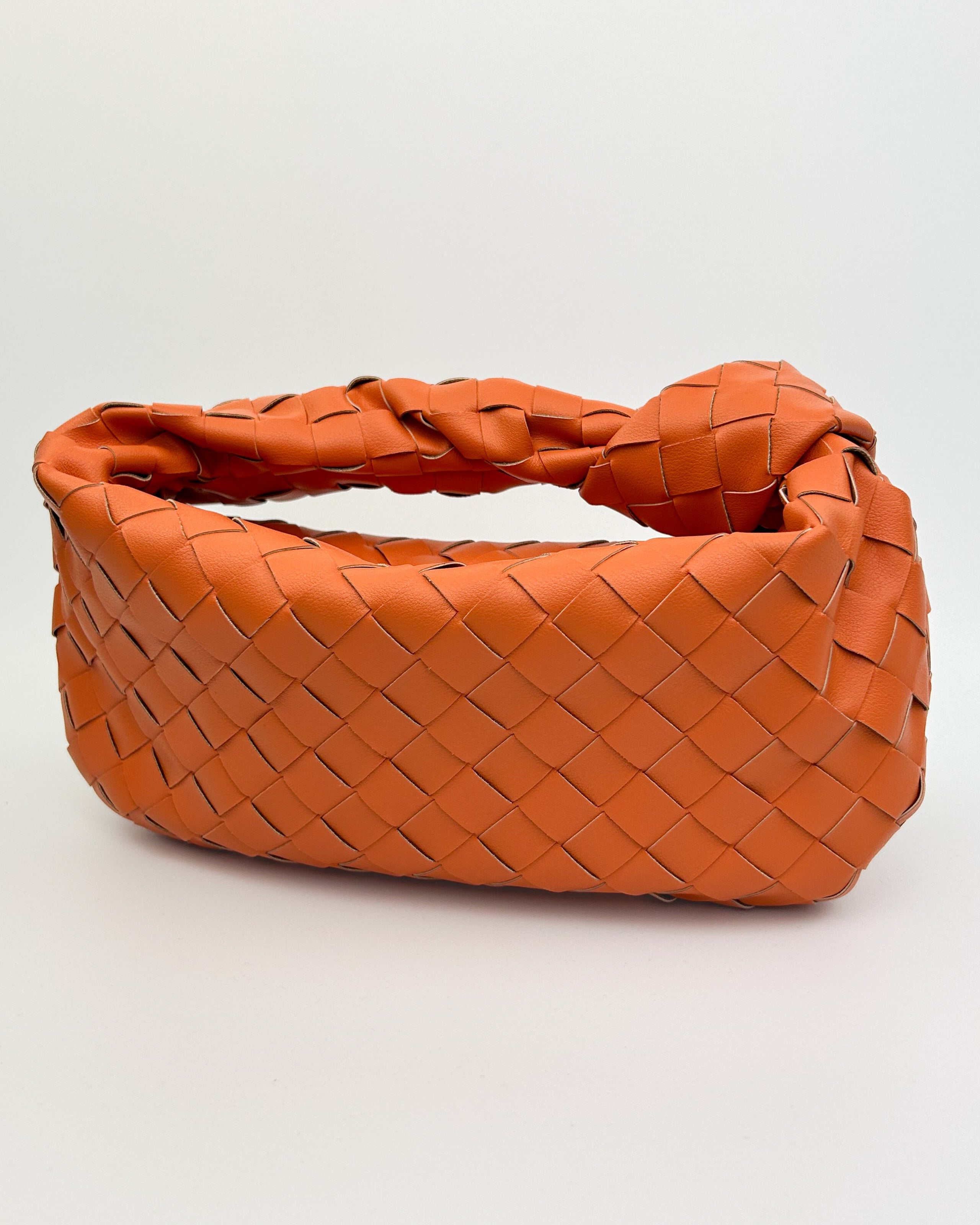 Detailed view of orange woven leather texture and signature knotted handle, handcrafted in Italy