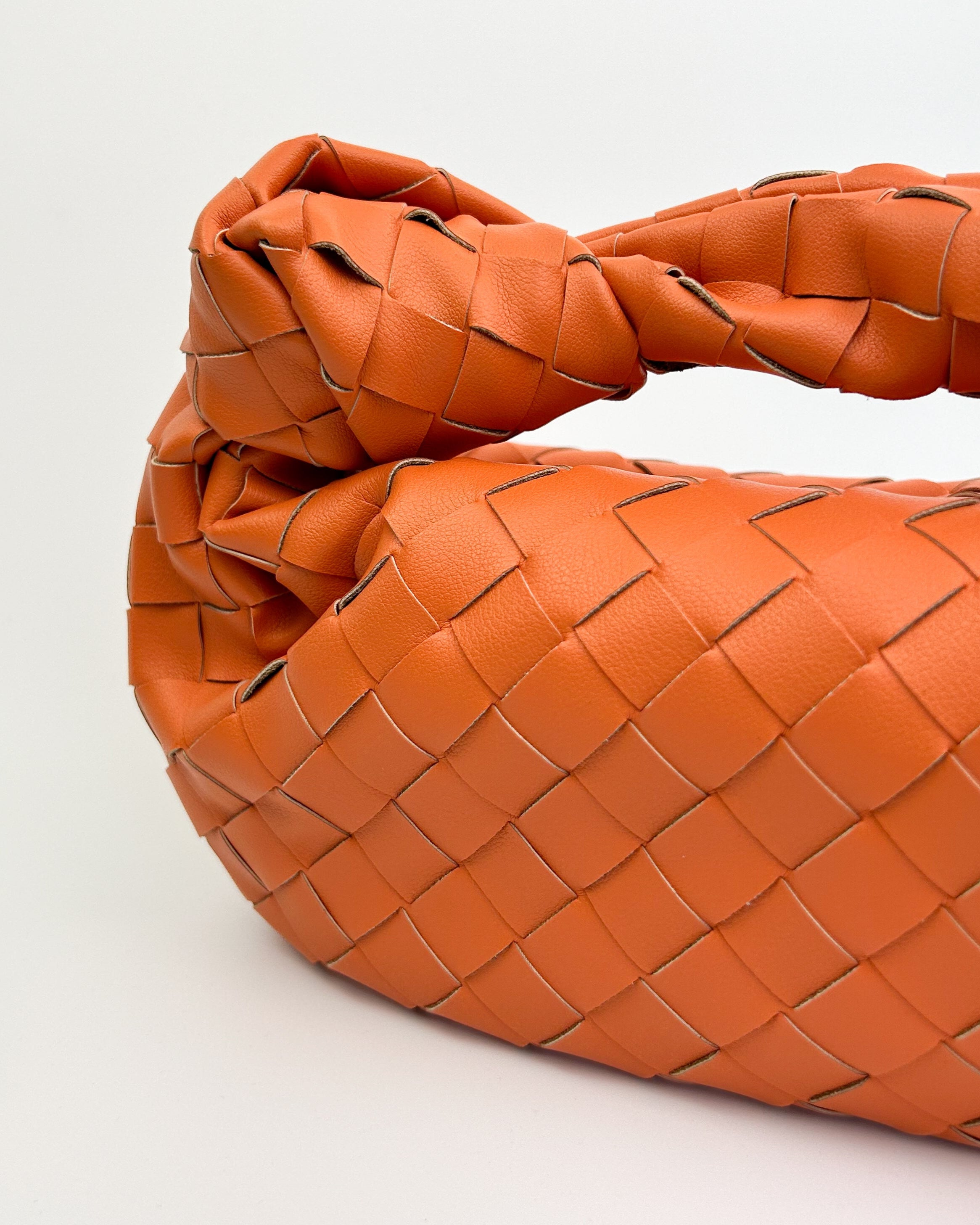 Interior view of The Knot Woven Bag in orange with zip closure, lined interior, and leather slip pocket