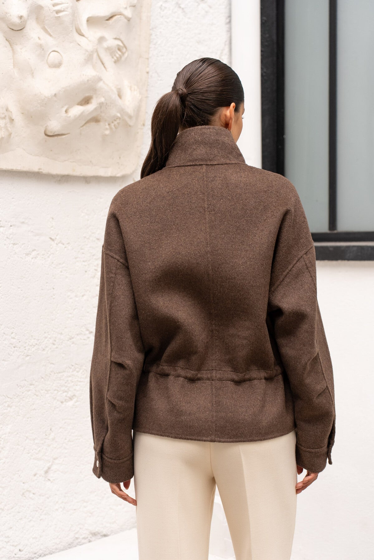 Back view of chocolate wool coat highlighting modern, relaxed silhouette.