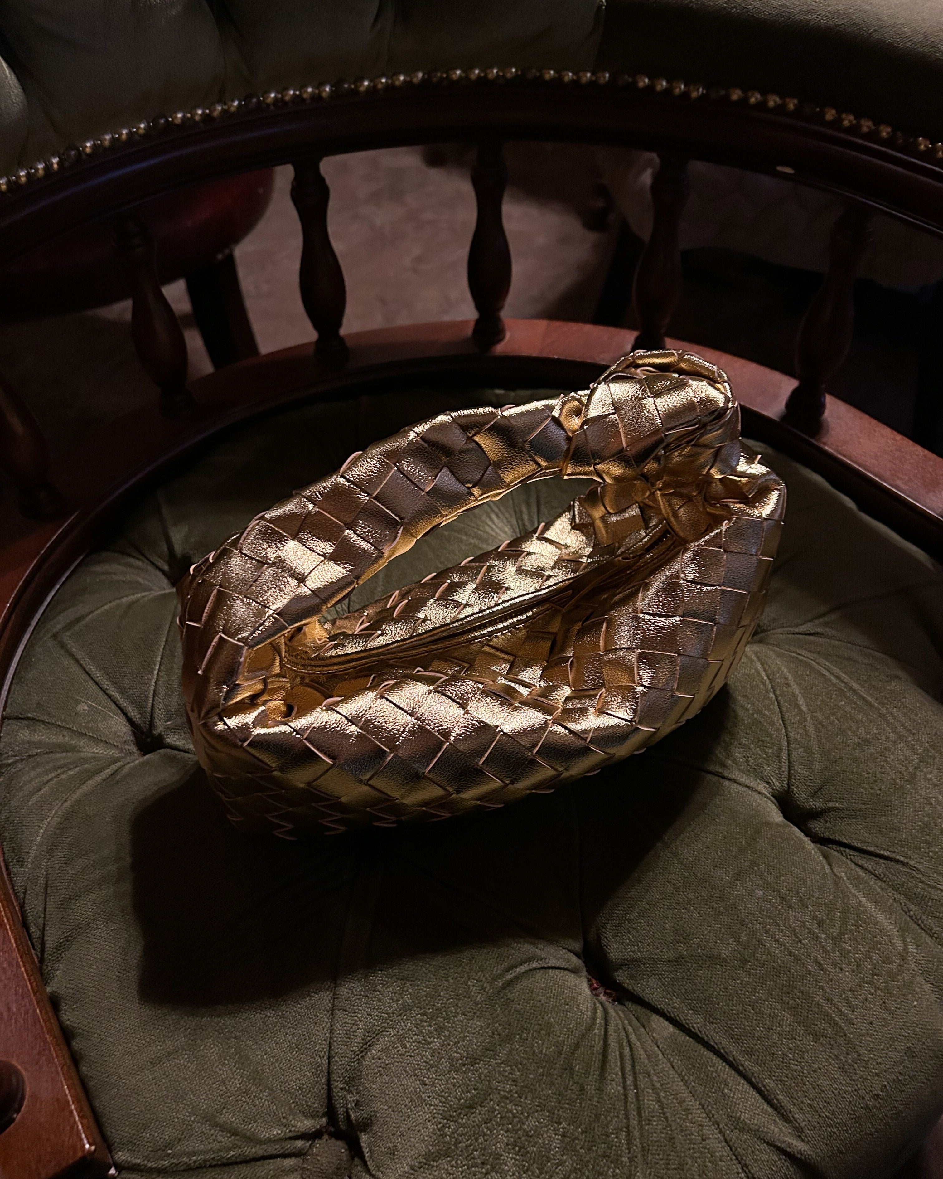 Gold woven bag displayed on the velvet chair 