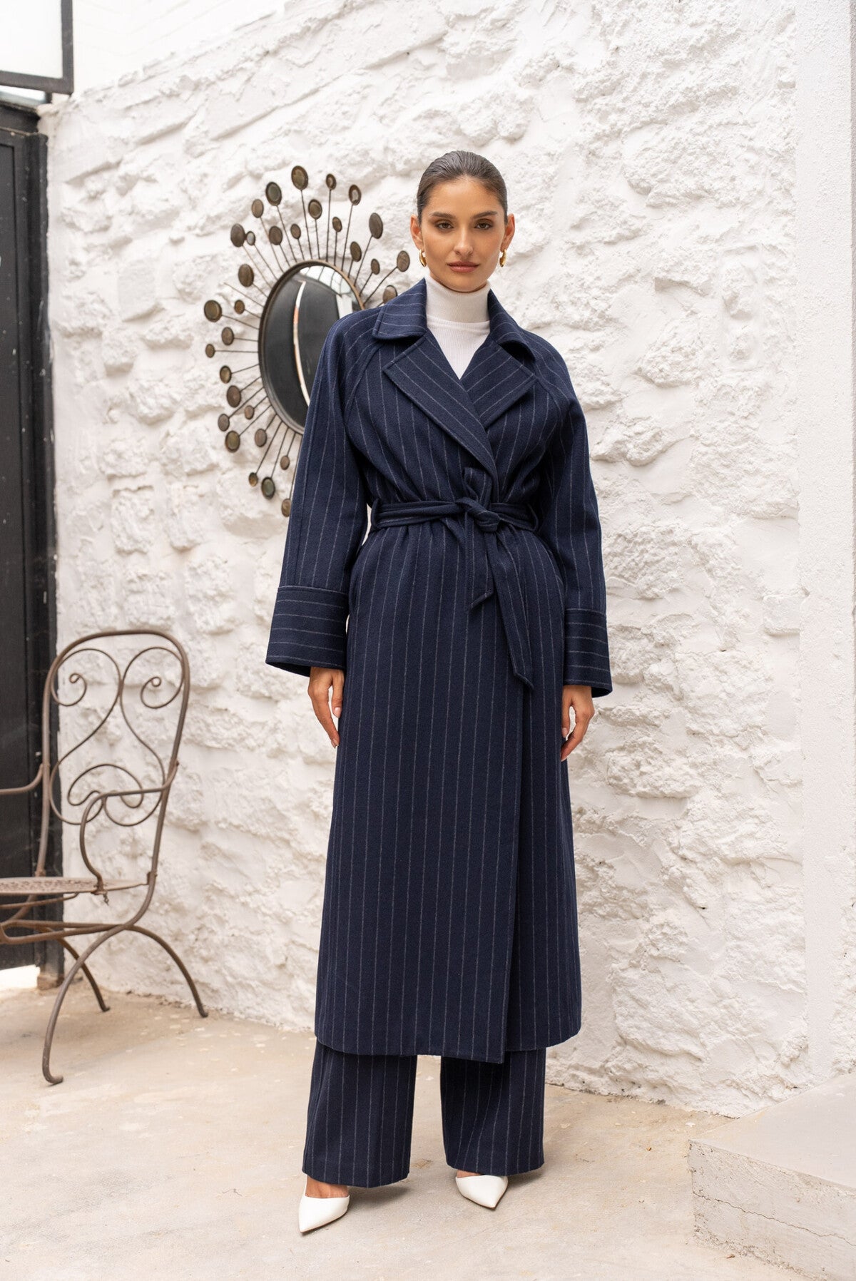 Model wearing Amelia long navy wool coat with belt and fine stripes.