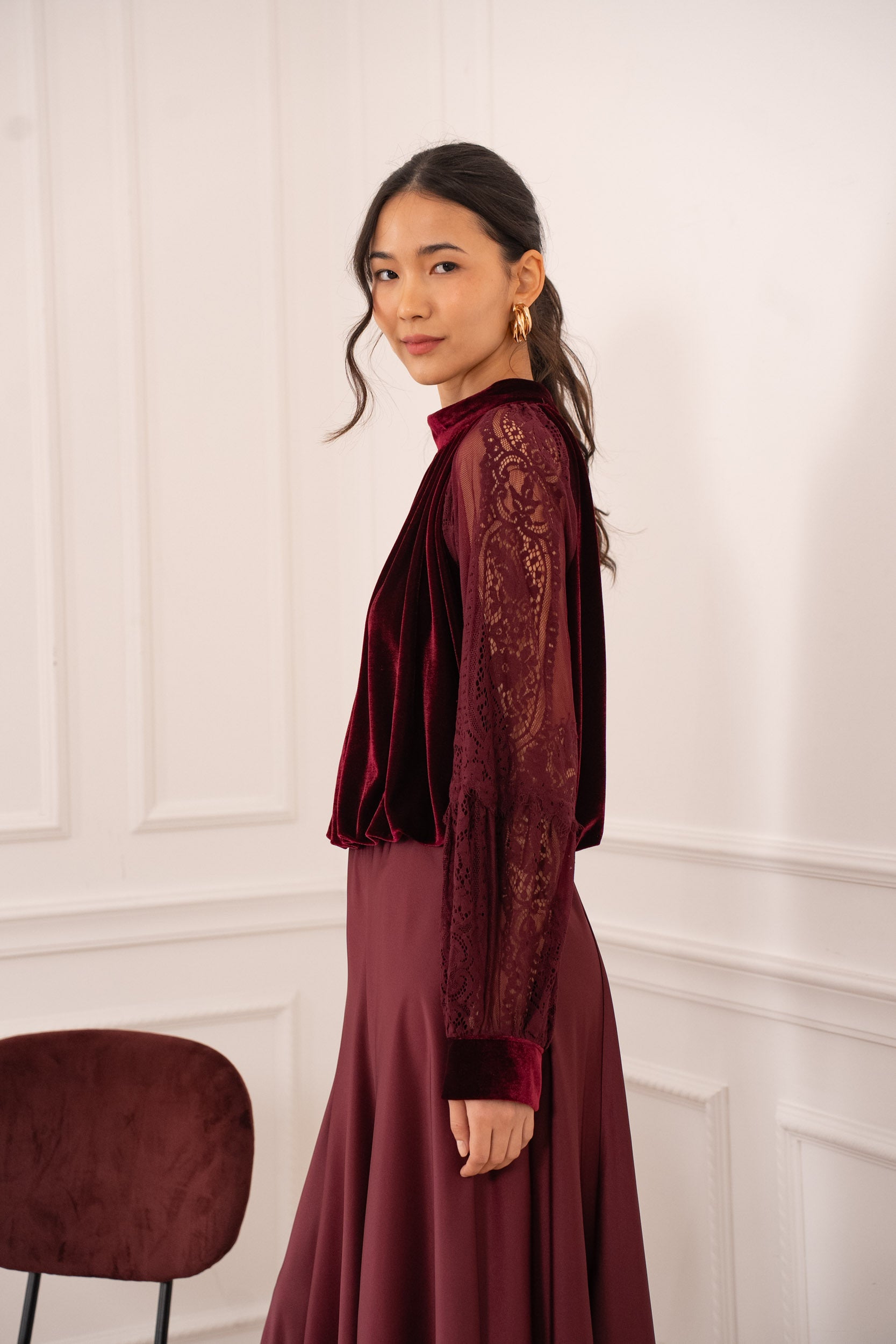 Burgundy velvet blouse detail showing intricate lace sleeve pattern and mock neck