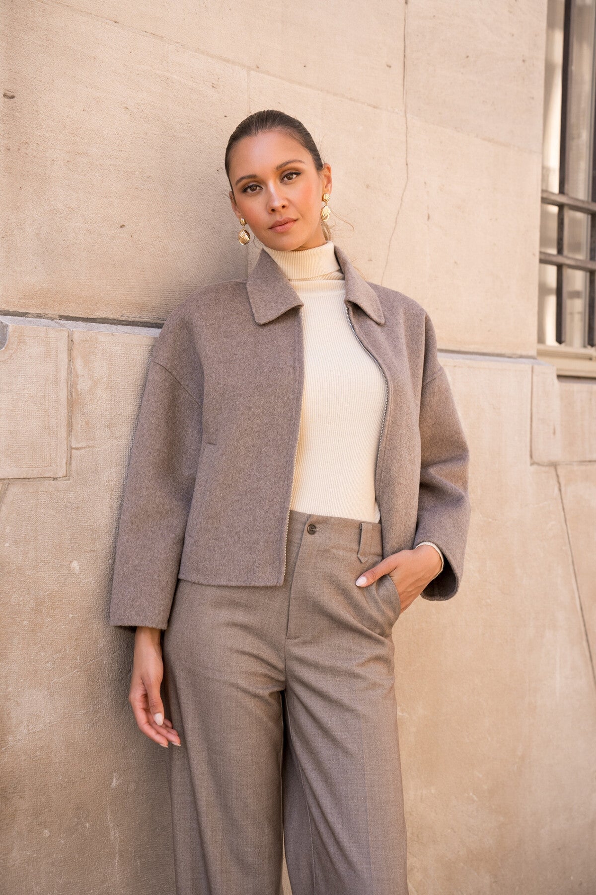 Model wearing taupe short wool coat with zip closure and structured loose fit.