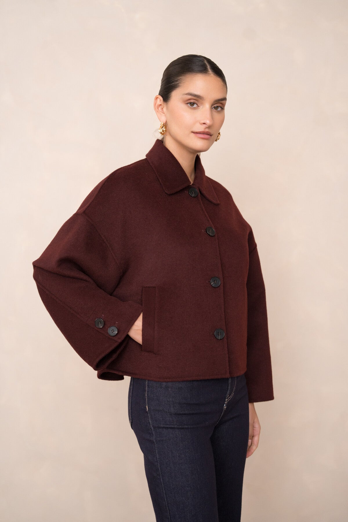 Side view of women’s burgundy wool coat showing discreet pockets and soft texture.