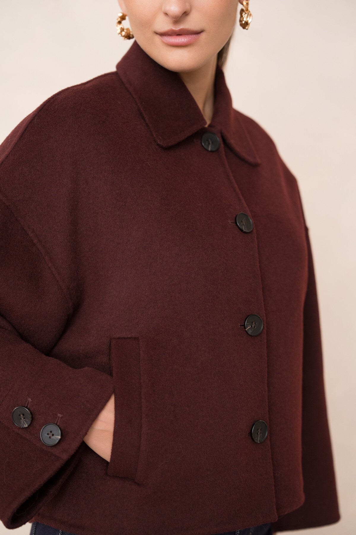 Close-up of burgundy wool blend fabric and contrasting button details.