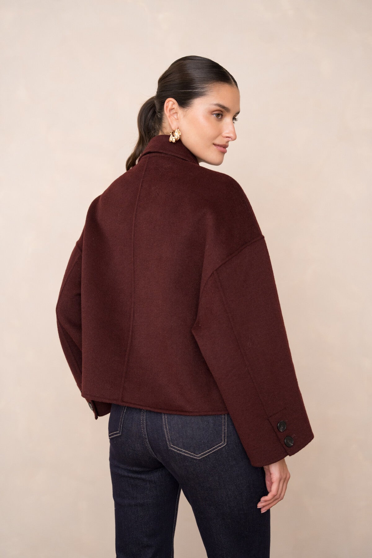 Back view of burgundy short coat showing loose, structured fit and flared sleeves.