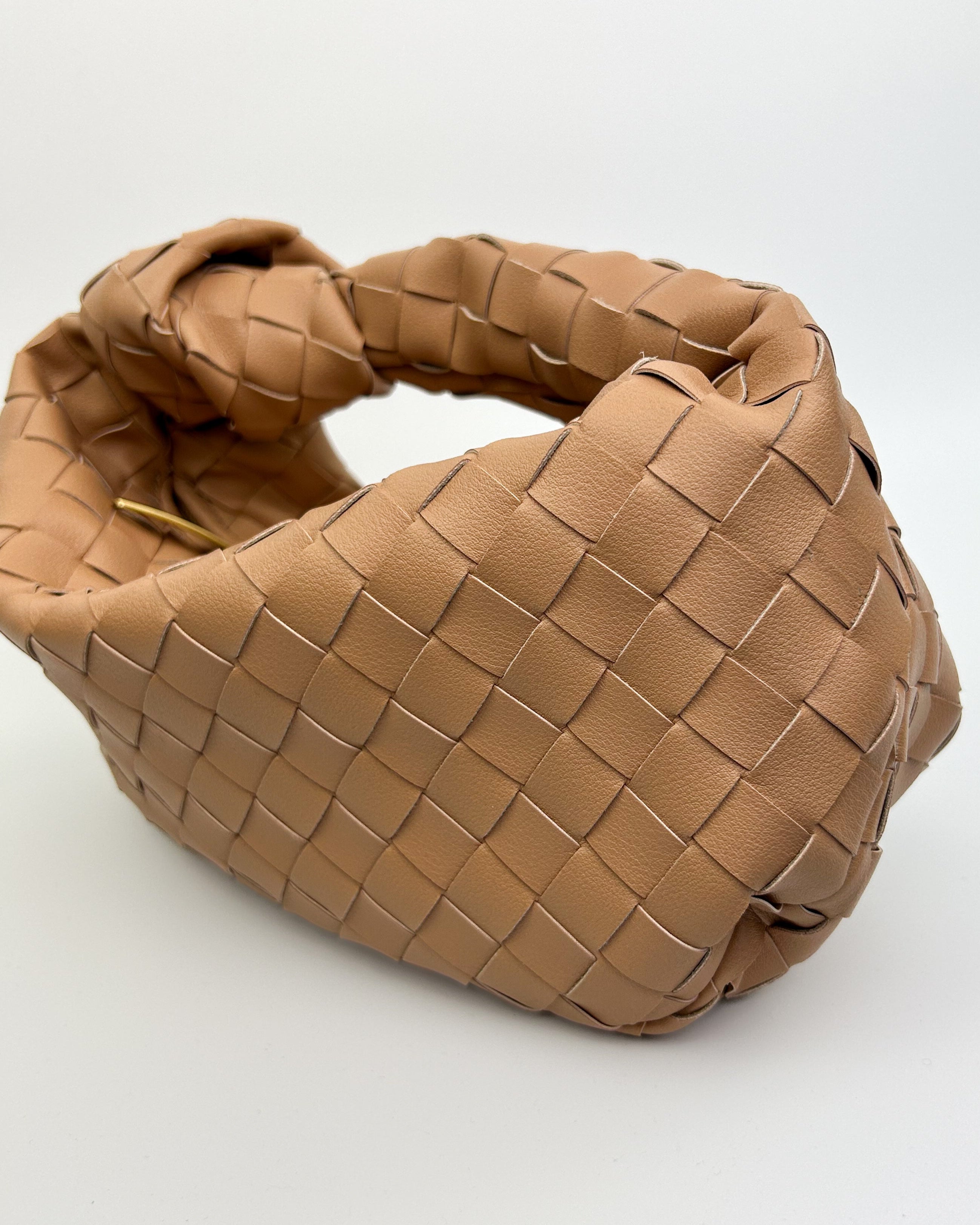 Sculptural crescent leather handbag with soft structure and premium woven detailing – side view of high-end Italian knot bag