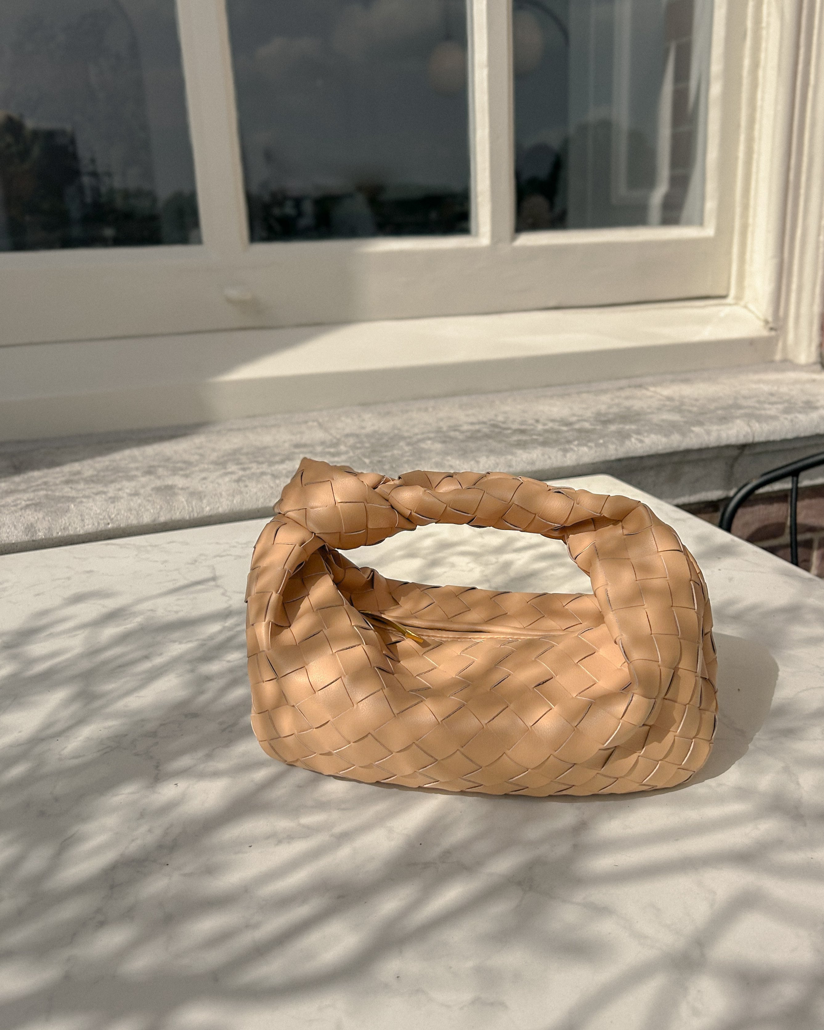 Woman styling The Knot Woven Bag, a real leather crescent handbag with knot detail, perfect for minimalist luxury outfits