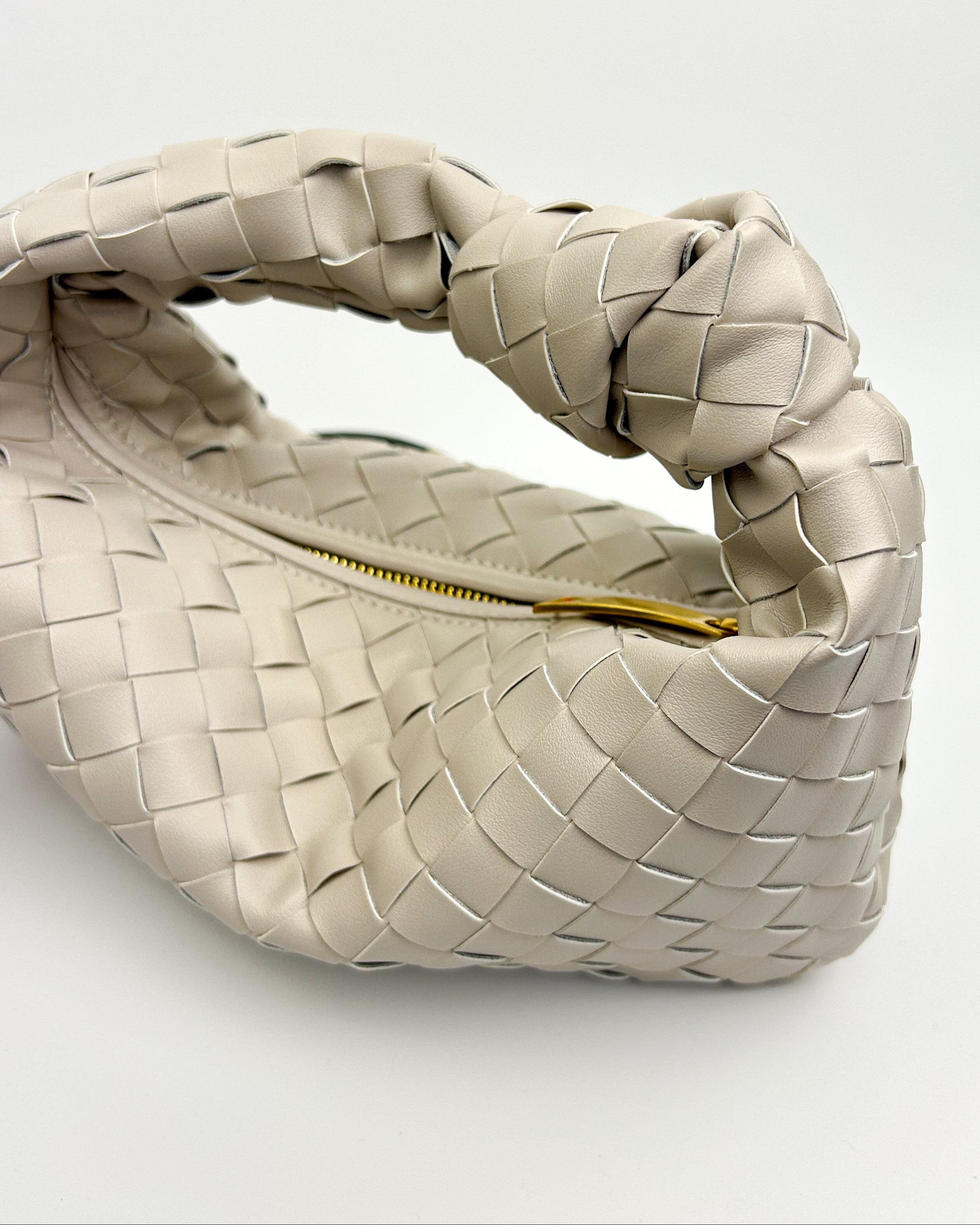 Side profile of sculptural oyster white crescent handbag in real leather, featuring structured artisan design