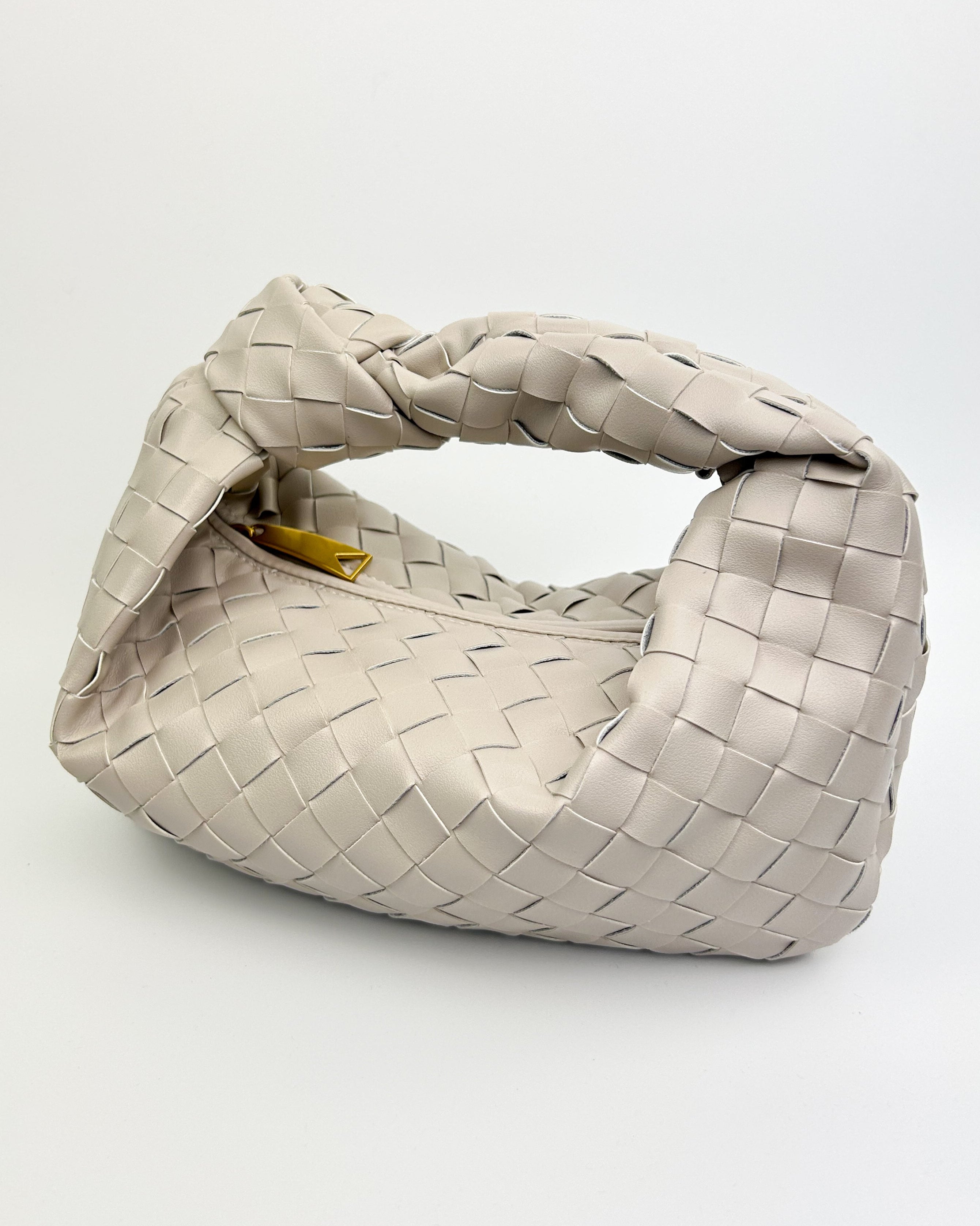 Interior of The Knot Woven Bag in oyster white with zip closure, soft lining, and leather slip pocket