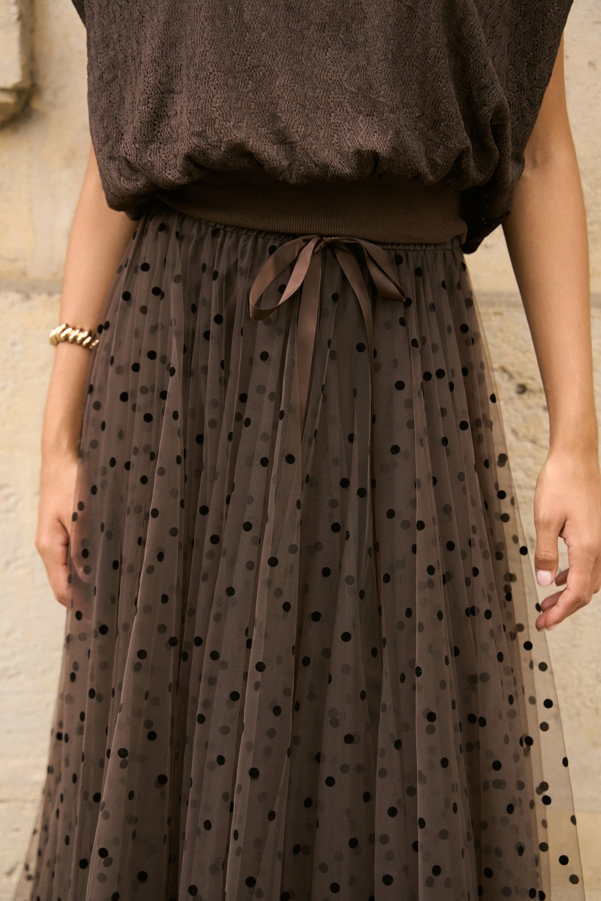 Close-up of chocolate brown tulle skirt with black polka dots, elasticated waist and satin bow